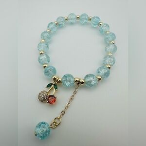 Elegant elastic bracelet of gold and blue beads with cherry charm